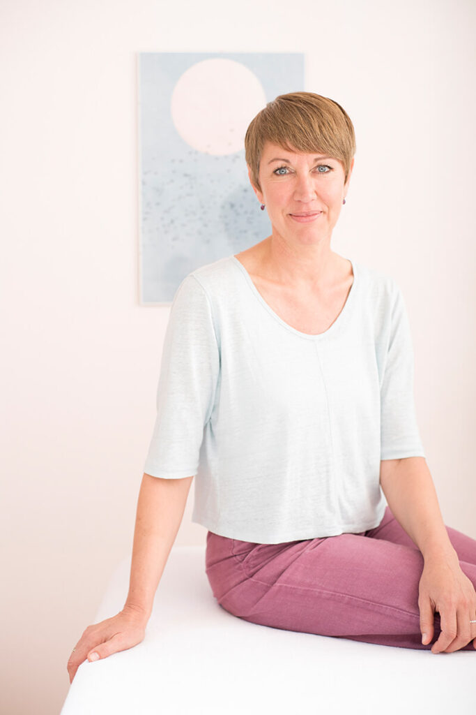 Maria Lanfranco sitzend auf einer Behandlungsliege.